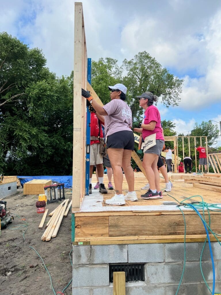 Women holding up a framing panel for installation